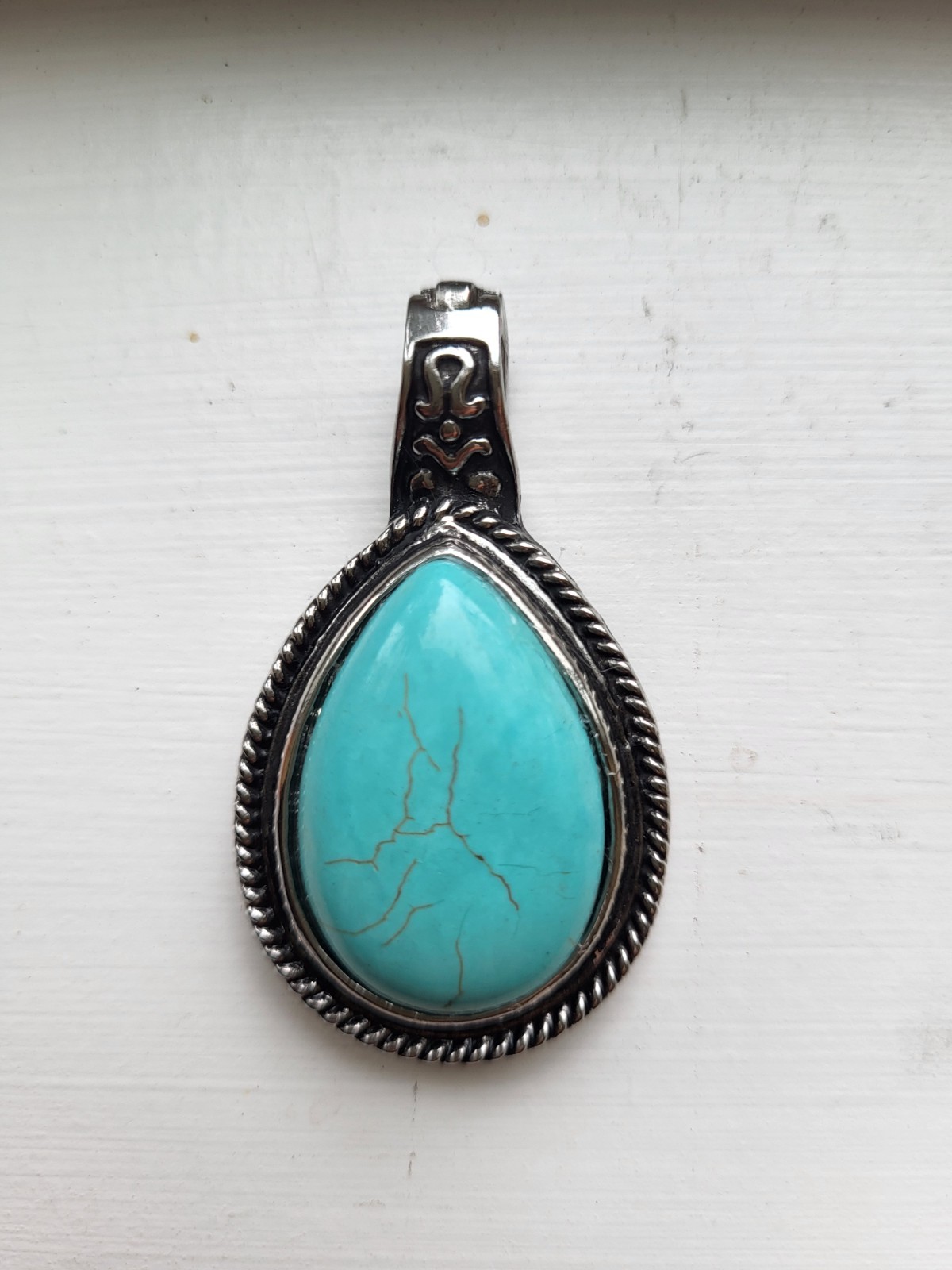 Teardrop-shaped faux turquoise stone pendant framed with detailed rope borders