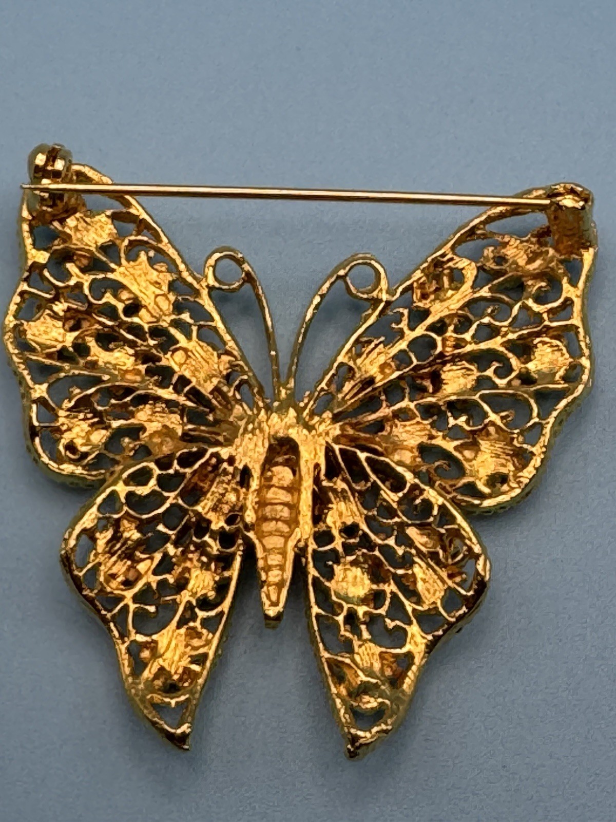 Butterfly brooch filigree gold-plated metal base. Amber colored rhinestones
