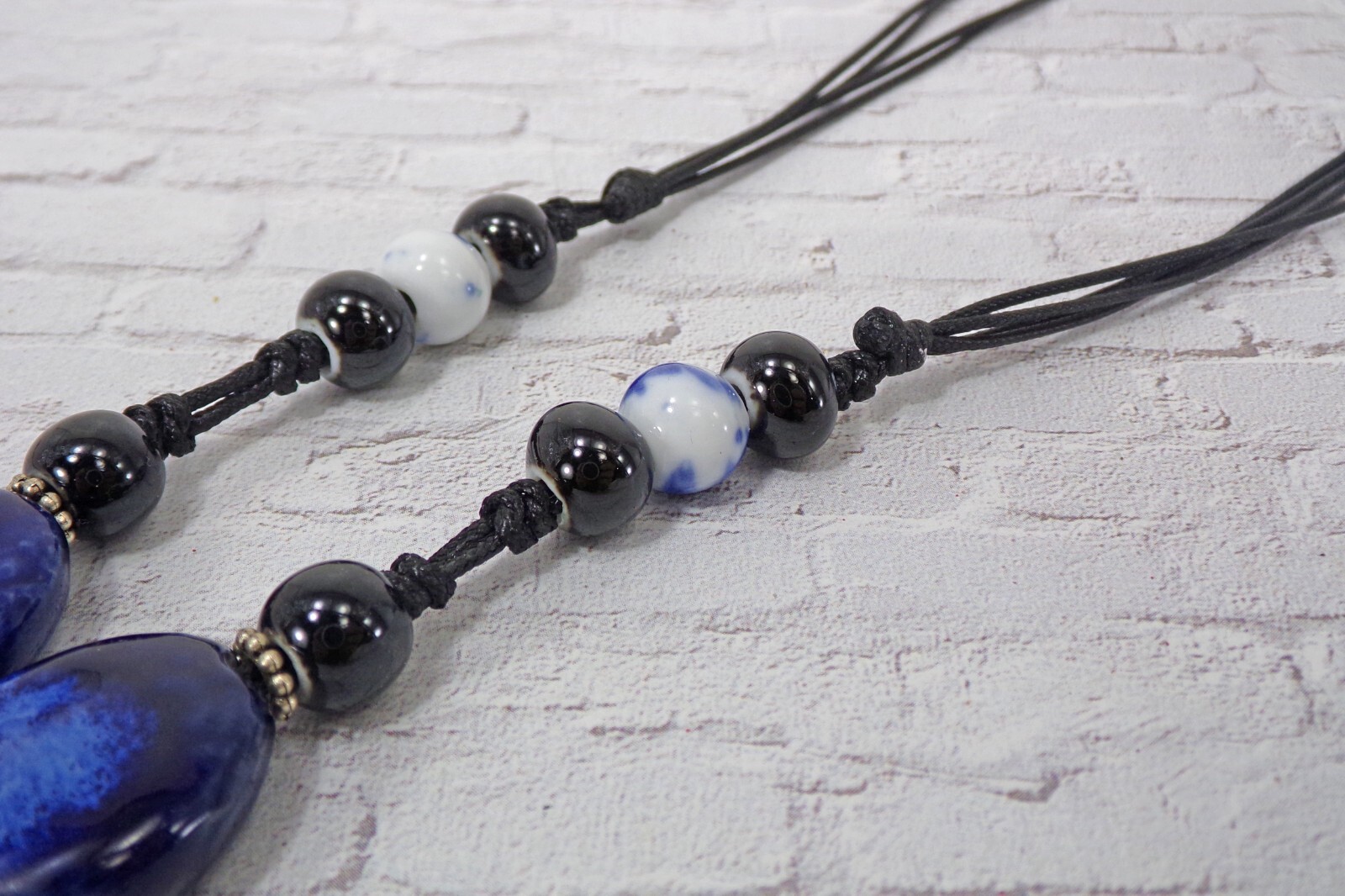 Blue ceramic bead tassel necklace with wood beads attached to a leather cord New