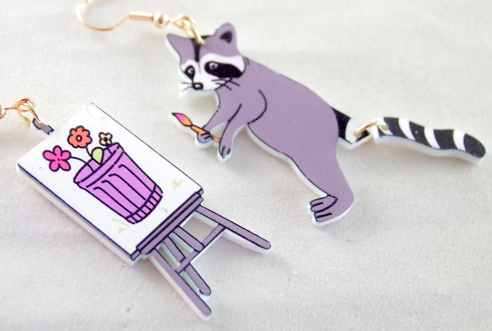 ASYMMETRICAL RACOON ARTIST PAINTING FLOWERS IN GARBAGE CAN ACRYLIC DROP EARRINGS