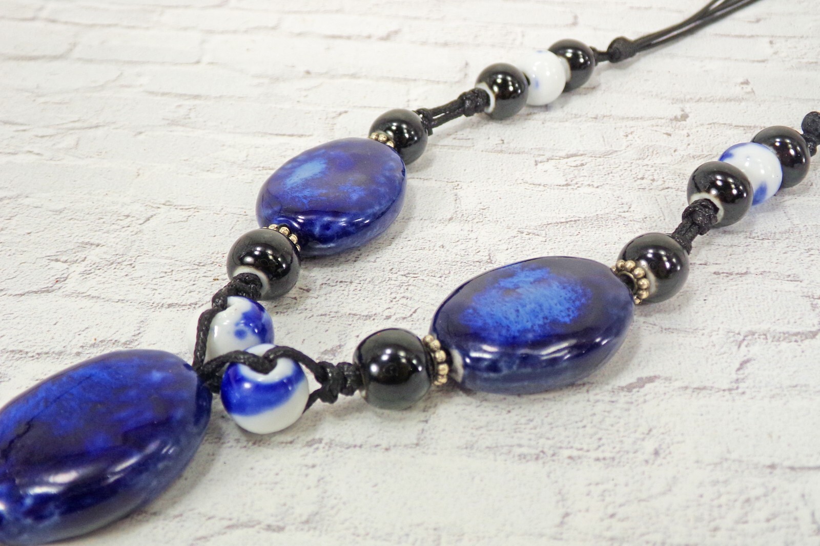 Blue ceramic bead tassel necklace with wood beads attached to a leather cord New
