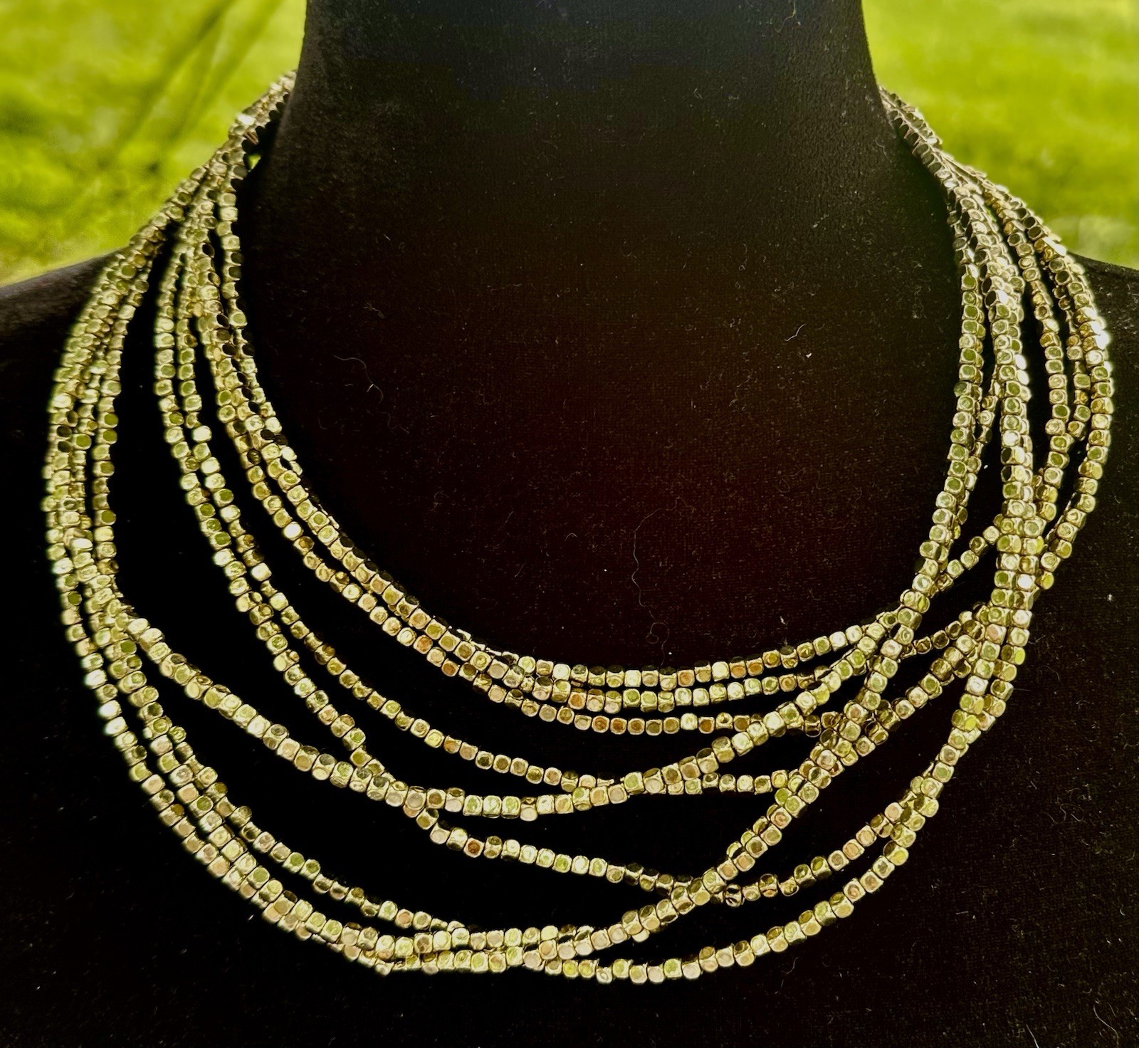 multi-strand bib necklace appears to be crafted from metallic-plated hematite
