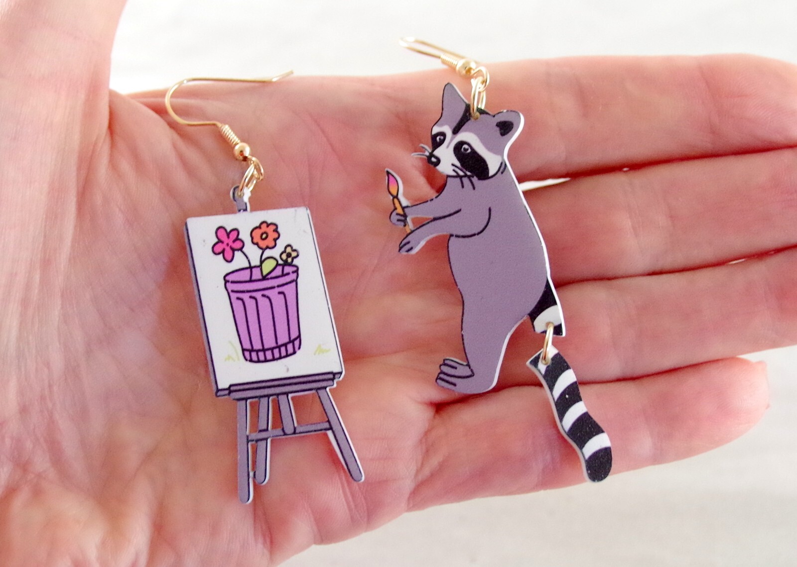 ASYMMETRICAL RACOON ARTIST PAINTING FLOWERS IN GARBAGE CAN ACRYLIC DROP EARRINGS