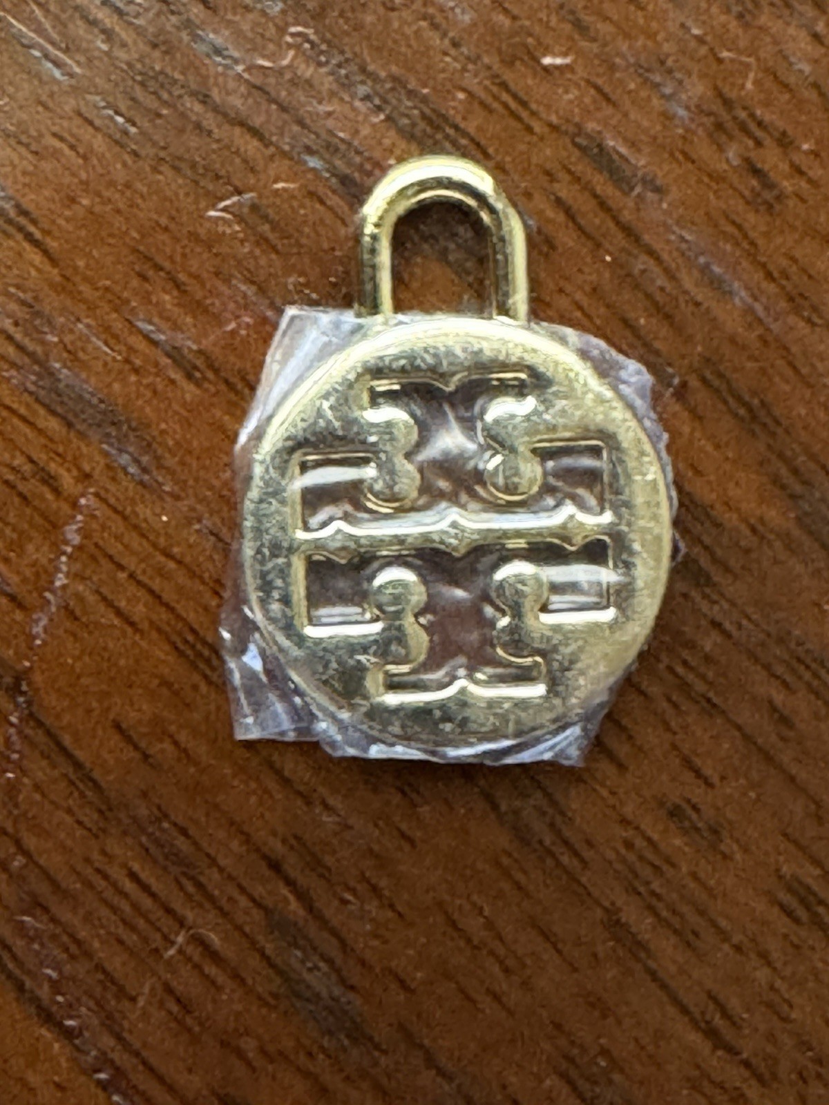 Tory Burch logo charm in gold tone Padlock-style loop for attaching to jewelry.