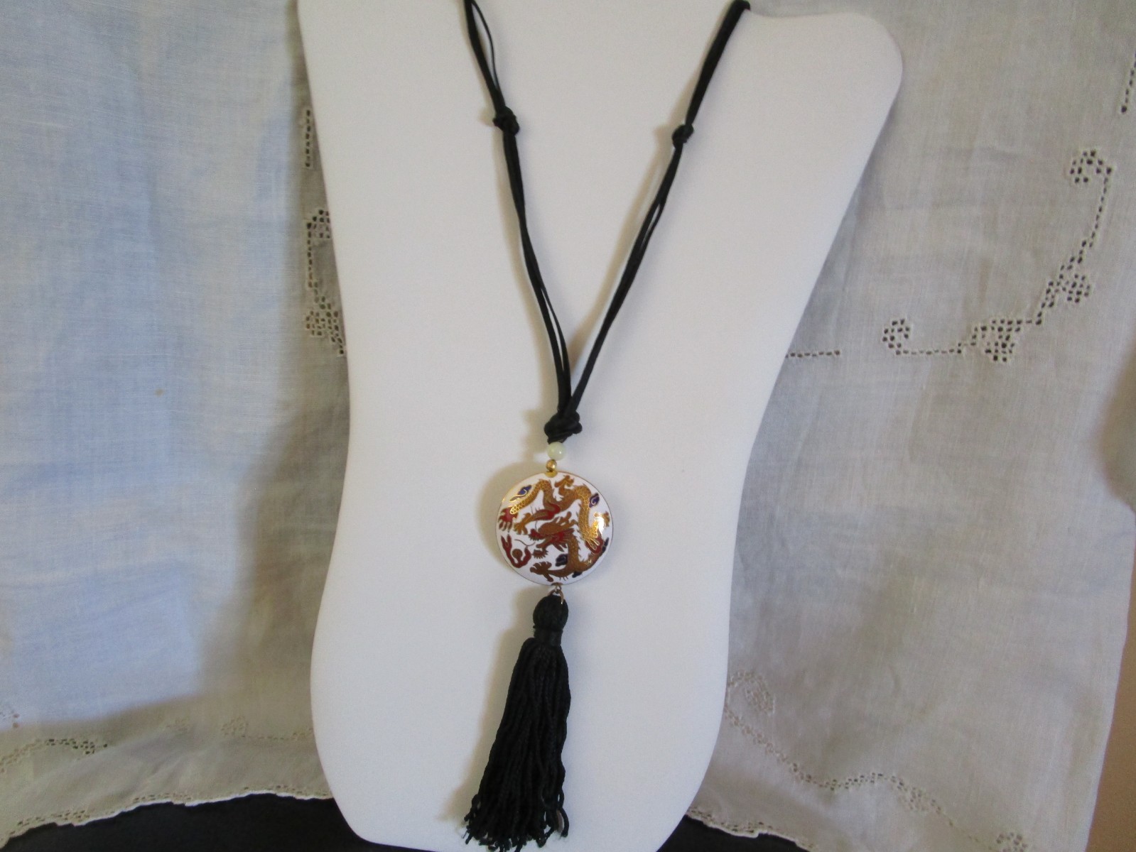 White porcelain with gold/red dragons round pendant on silk black cord. NOV25-36