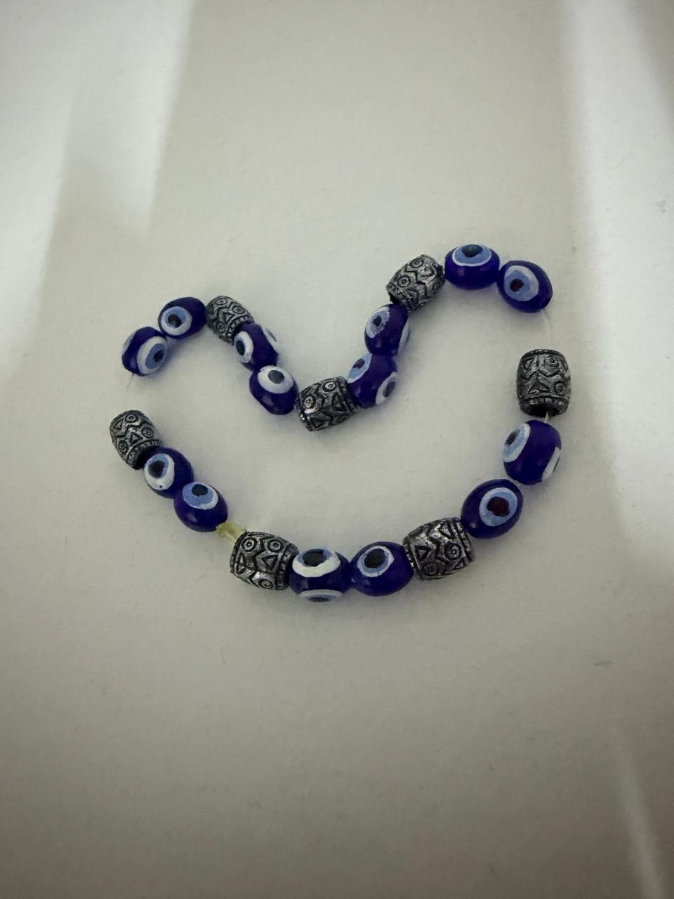 Blue Evil Eye Beaded Bracelet With Silver Accents On White Surface Clean Style.