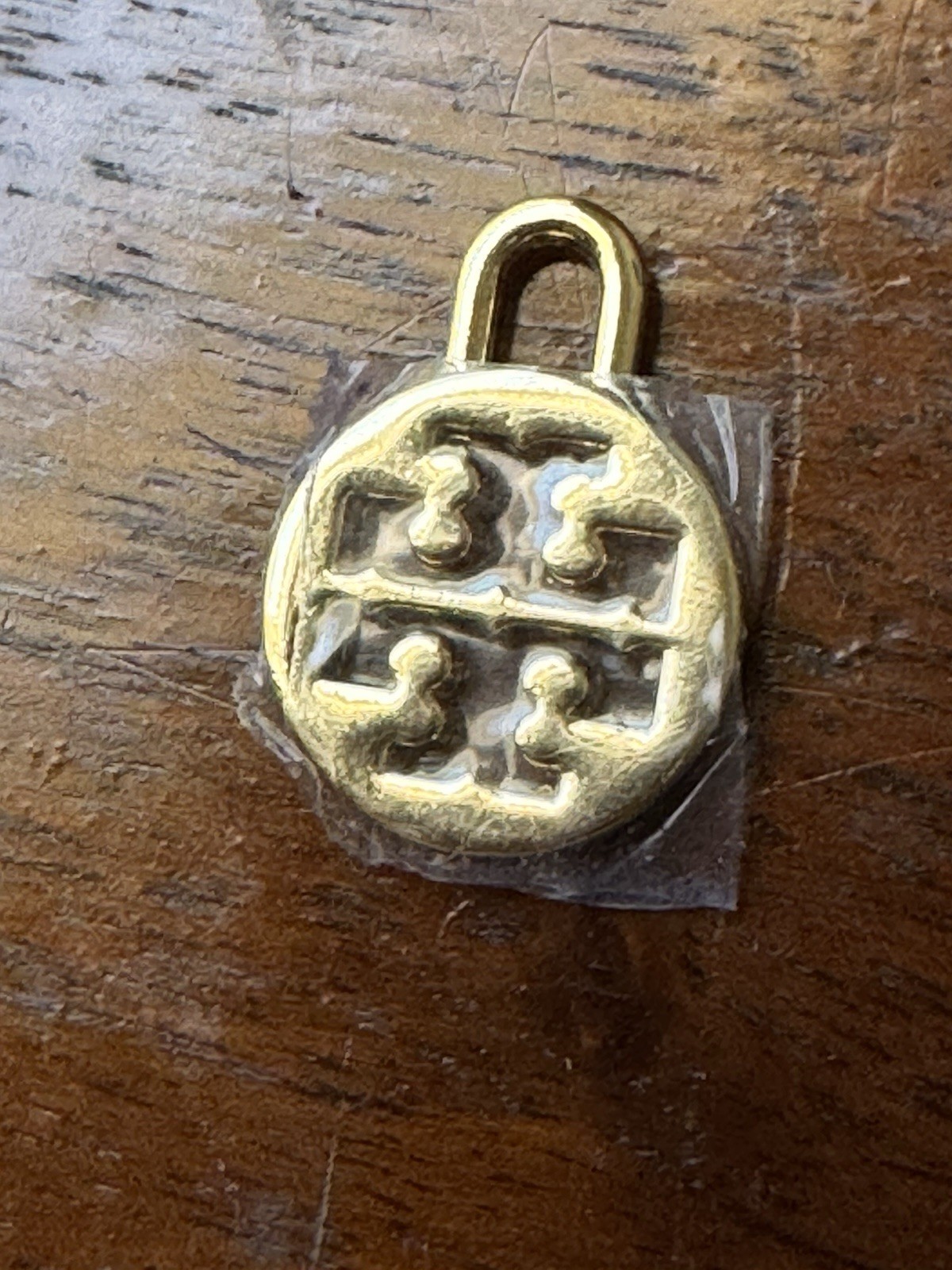 Tory Burch logo charm in gold tone Padlock-style loop for attaching to jewelry.