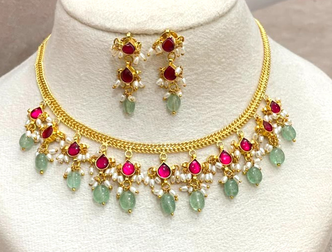 Necklace includes prominent pink stones and green bead drops