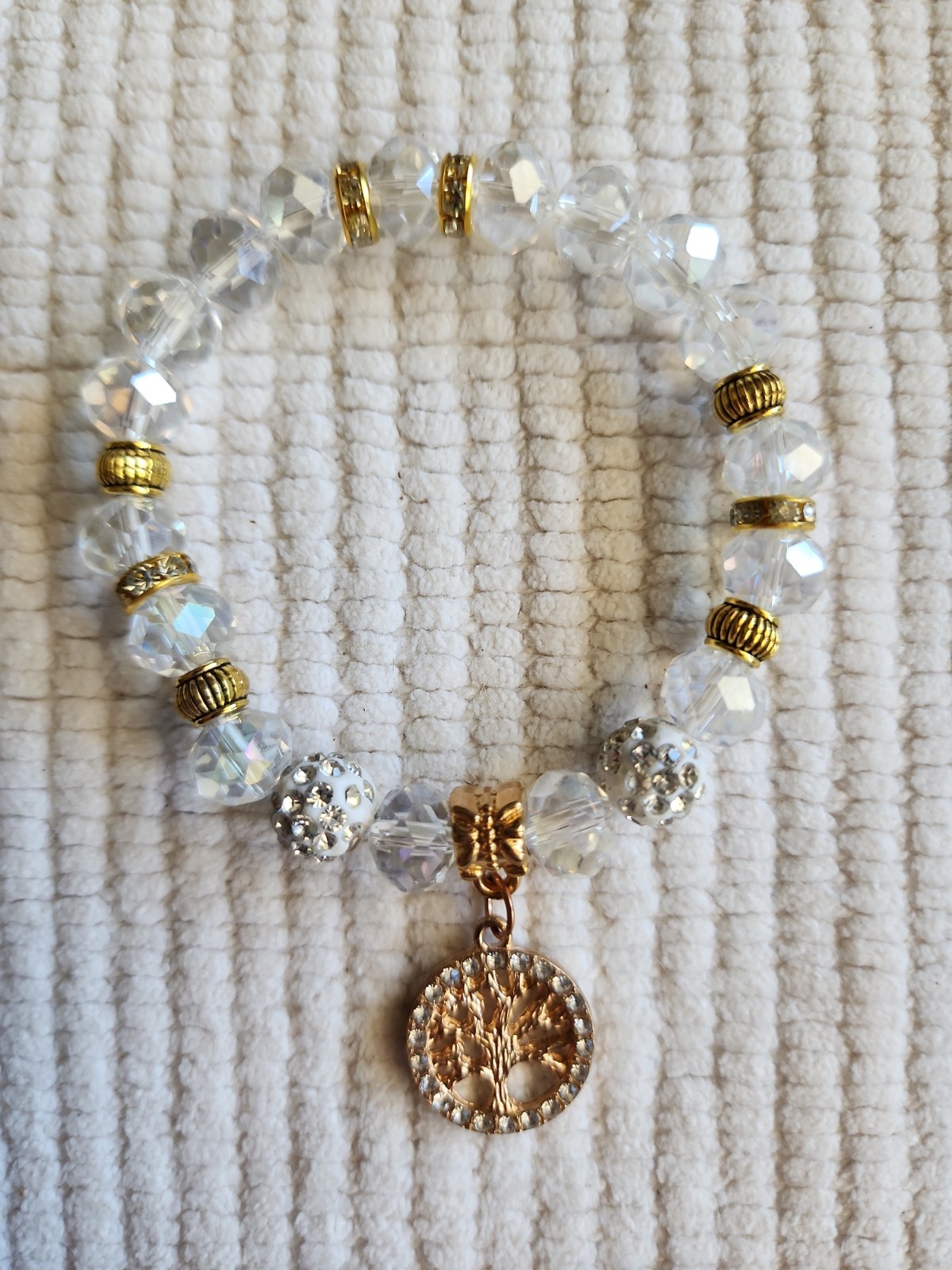 Beaded bracelet with a tree of life charm and crystal and gold-toned beads.