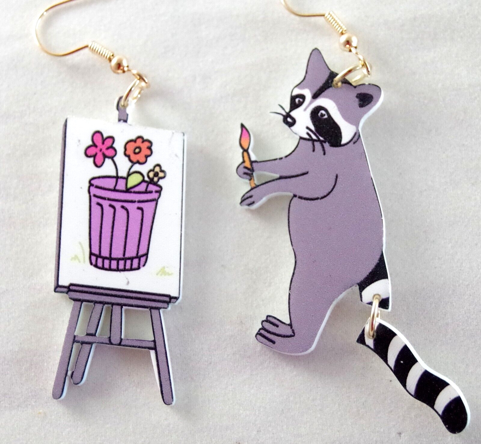 ASYMMETRICAL RACOON ARTIST PAINTING FLOWERS IN GARBAGE CAN ACRYLIC DROP EARRINGS